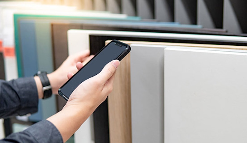 Digital inventory tracking system in a warehouse A warehouse employee using a digital device to scan inventory items on shelves
